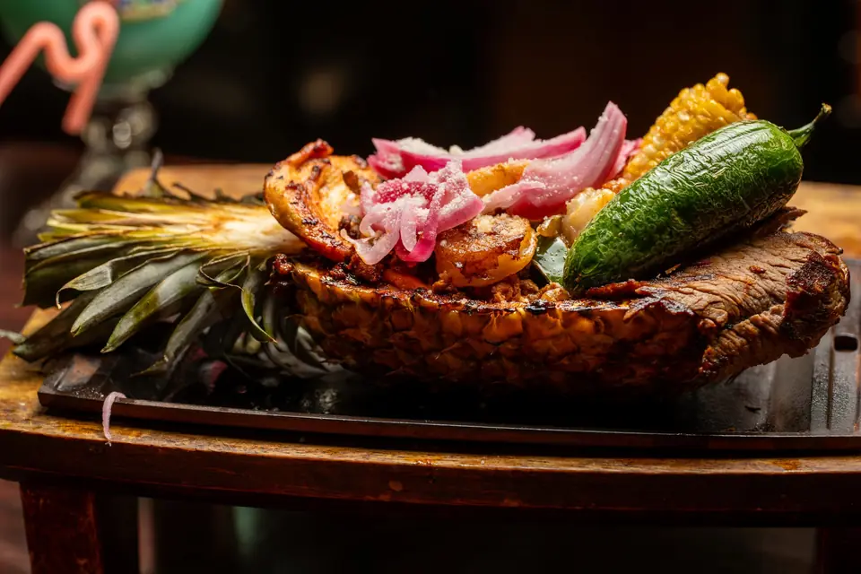 Carved pineapple platter with grilled shrimp, pickled onion and corn