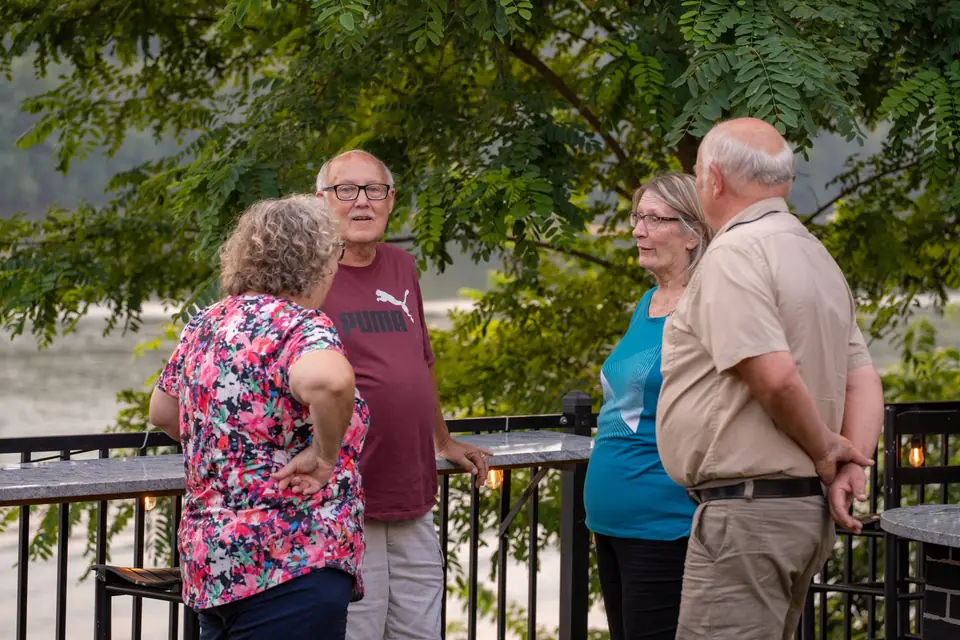 Friends talking at the railing above the river